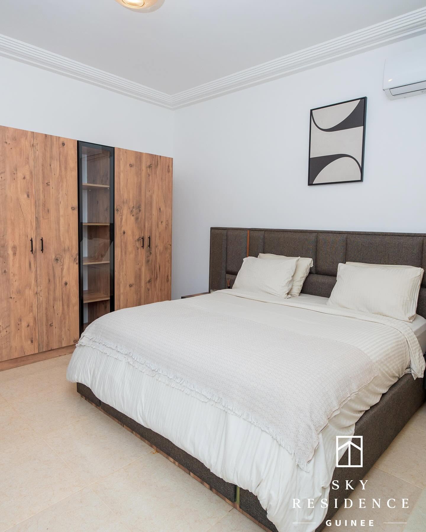 Chambre Sky Residence avec dressing en bois et literie blanche