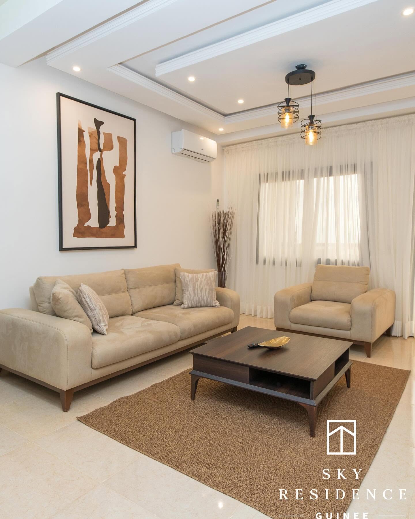 Salon beige Sky Residence avec œuvre d'art et faux plafond